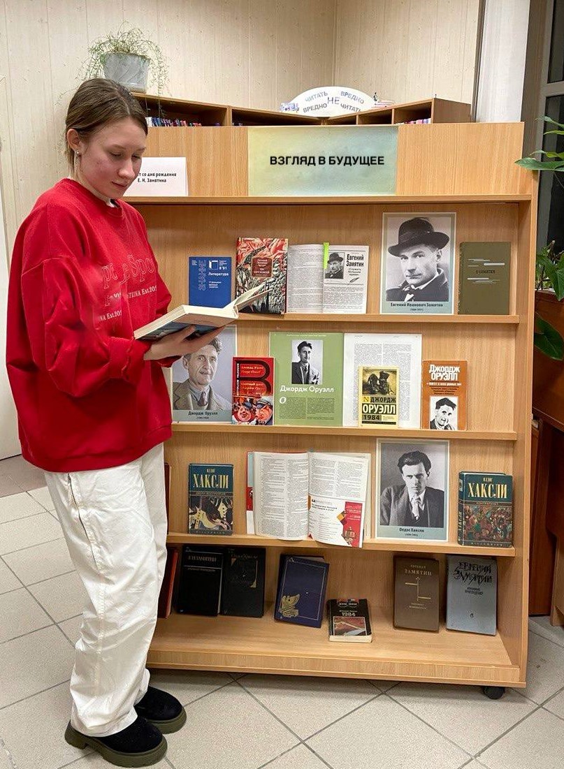 МБКПУ Печенгское МБО девушка смотрить книги у книжной выставки Взгляд в будущее